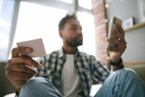 Man looking at mobile with cards in hand