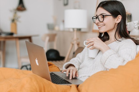 Girl sitting with laptop and having cup in her hand