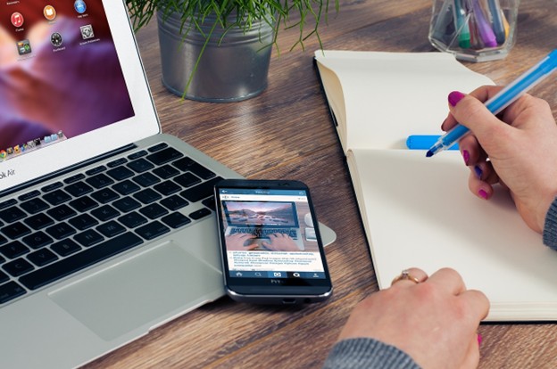 women hand with pen and copybook, laptop and iphone